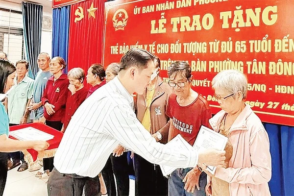 Trao thẻ Bảo hiểm y tế cho người cao tuổi phường Tân Đông Hiệp. (Ảnh: VÕ LÊ)