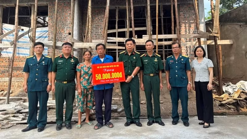 Cựu chiến binh Phạm Văn Lượng (đứng giữa) nhận hỗ trợ xây nhà mới. (Ảnh: NGỌC LAN)