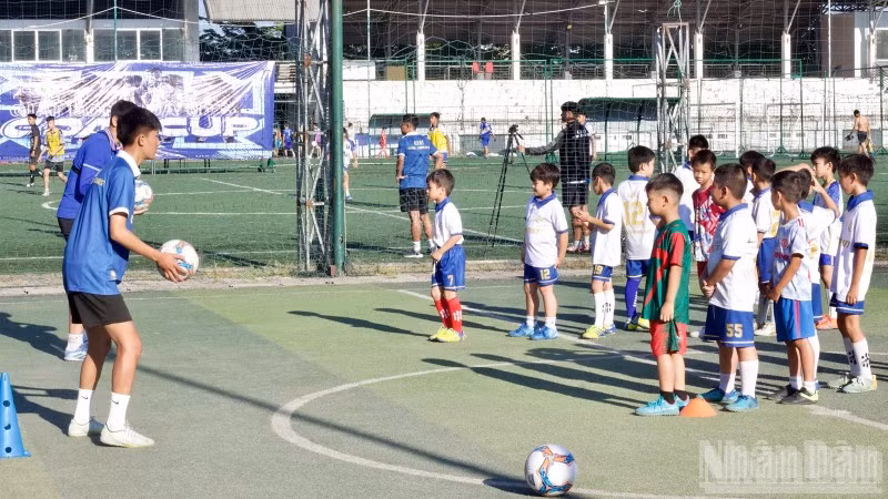 Các cầu thủ nhí học kỹ năng đá bóng cùng huấn luyện viên.