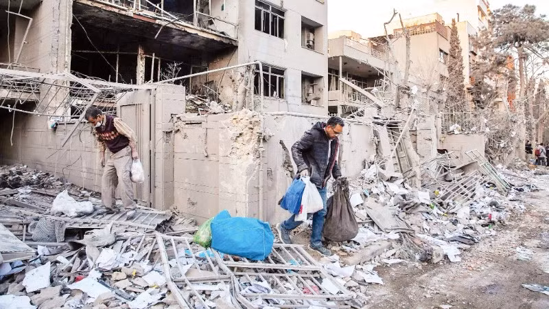 Người dân thu dọn đống đổ nát sau một vụ không kích tại Iran. (Ảnh: THE NEW YORK TIMES)