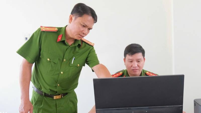 Thượng tá Cao Thành Nhân (trái) hướng dẫn cán bộ hoàn chỉnh hồ sơ quản lý địa bàn. (Ảnh: Đăng Khoa)