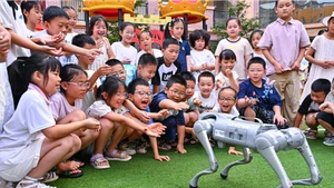 Trẻ em “giao lưu” với chó robot ở huyện Nhân Thọ, thành phố My Sơn, tỉnh Tứ Xuyên, Trung Quốc. (Ảnh: Tân Hoa Xã)
