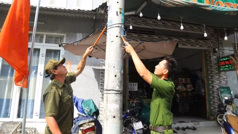 Cán bộ, chiến sĩ Công an Thành phố Hồ Chí Minh tham gia bóc xóa quảng cáo trái quy định.