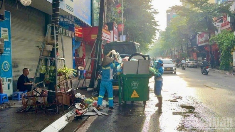Công nhân môi trường dọn dẹp, thu gom rác sau mưa bão trên phố Khâm Thiên (Hà Nội). 