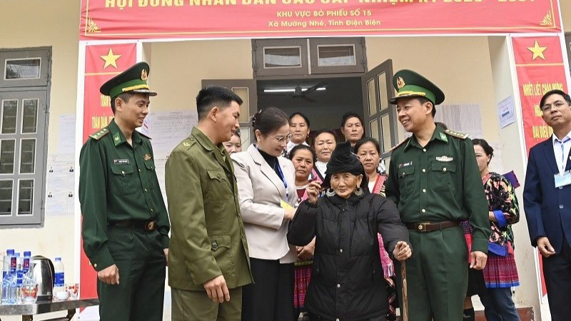 Đại tá Lê Đức Nghĩa cùng cán bộ, nhân dân xã Mường Nhé trò chuyện, động viên cử tri cao tuổi nhất tỉnh Điện Biên là cụ bà Trá Thị Dềnh ở bản Nậm Là 2, xã Mường Nhé.