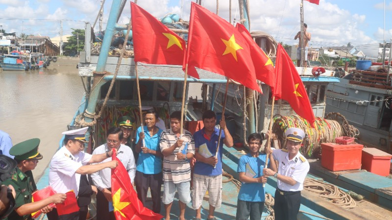 Ngư dân xã Đại An, tỉnh Vĩnh Long được cán bộ, chiến sĩ Hải quân Vùng 2 trao tặng cờ Tổ quốc.