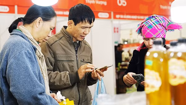 Người dân dùng điện thoại để truy xuất thông tin các sản phẩm nông sản. Ảnh: NAM ANH