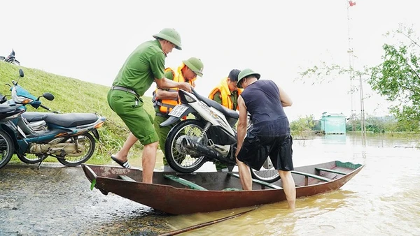 Công an xã Lam Thành (Nghệ An) hỗ trợ người dân vận chuyển xe máy lên đê tránh lũ.