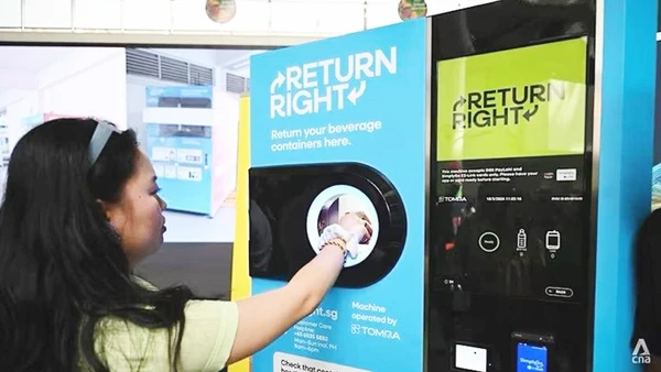 Một người tiêu dùng đặt chai nhựa rỗng vào máy thu gom. Ảnh: CNA