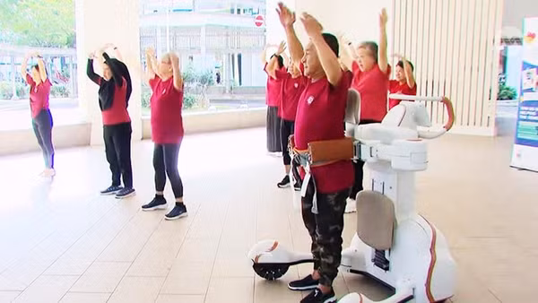 Ông Leow Cher Hwa tham gia lớp học Zumba với sự hỗ trợ trực tiếp từ robot hỗ trợ vận động. Ảnh: CNA