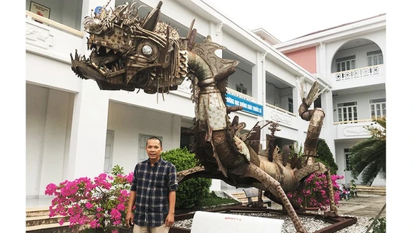 Họa sĩ Đinh Thanh Hải bên tác phẩm “Con rồng sắt” của nhà điêu khắc Pháp Marc Morvan, làm bằng phế liệu vỏ bom đạn, inox sau chiến tranh, hiện đặt tại sân Trường đại học Khánh Hòa.