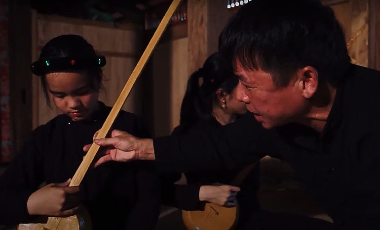 Nghệ nhân Dương Hữu Cà đang hướng dẫn các em nhỏ học hát then, đàn tính.