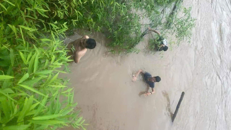 Thời điểm hai người dân đưa được lái xe vào bờ.