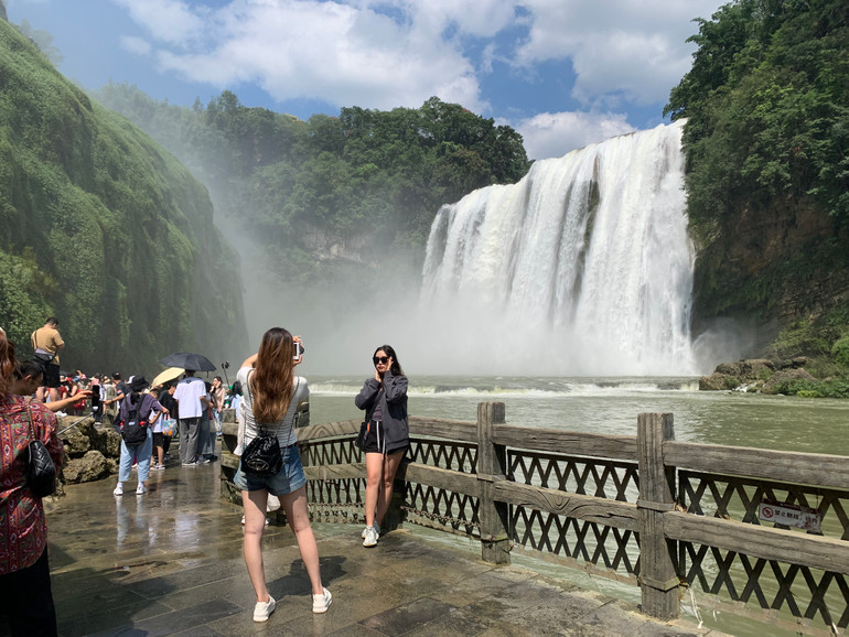 Du khách lưu lại khoảnh khắc đẹp bên thác chính. (Ảnh: HỮU HƯNG)