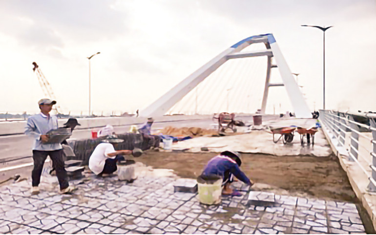 Công nhân lát gạch vỉa hè khu vực ngắm cảnh bên thành cầu Trần Hoàng Na.