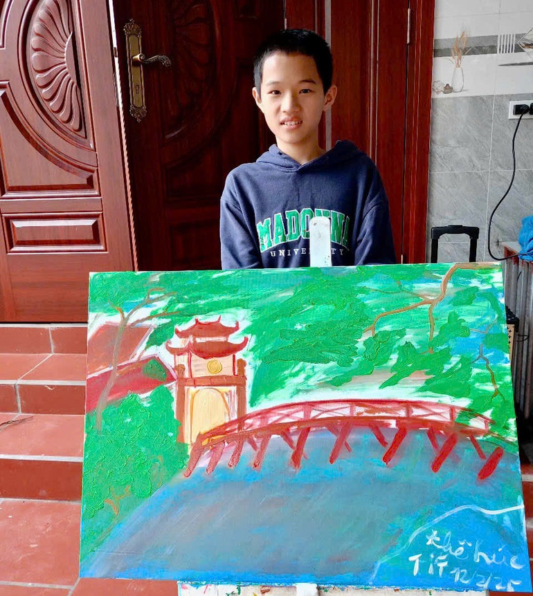 Bé Bảo Nam với bức tranh vẽ cầu Thê Húc. (Ảnh: VĂN CHỨC)