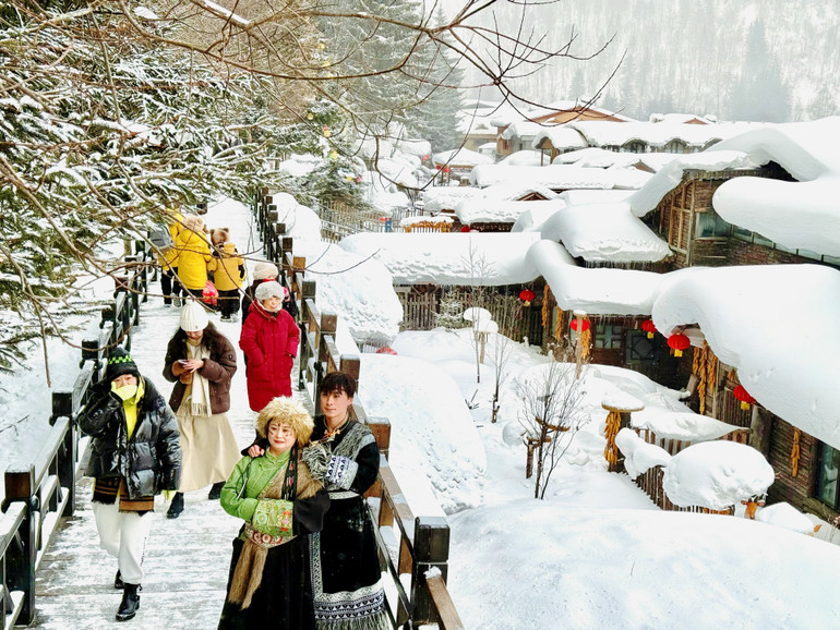 Du khách trong trang phục truyền thống check-in bên những mái nhà phủ đầy tuyết trắng.