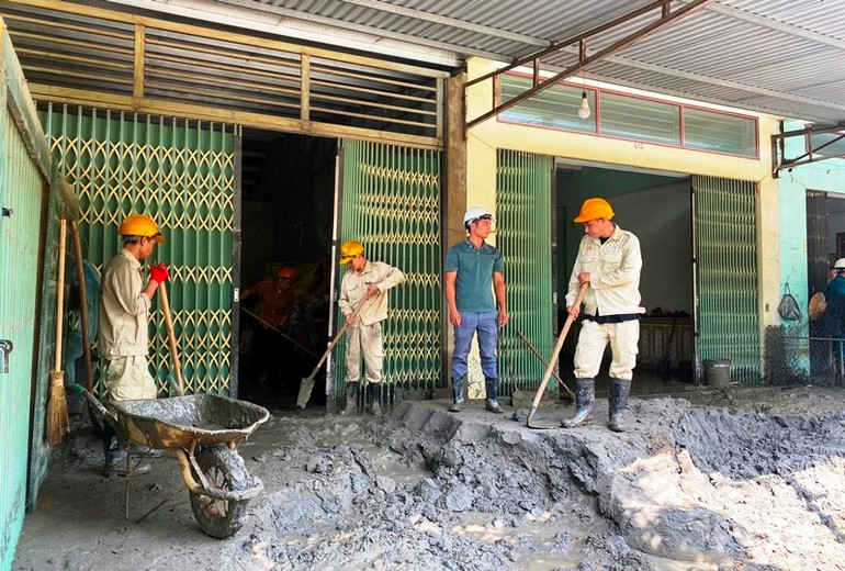 Công nhân Nhà máy tuyển đồng Tả Phời giúp người dân khắc phục hậu quả do sự cố vỡ cống xả tràn hồ thải nhà máy gây ra. (Ảnh: QUỐC HỒNG)
