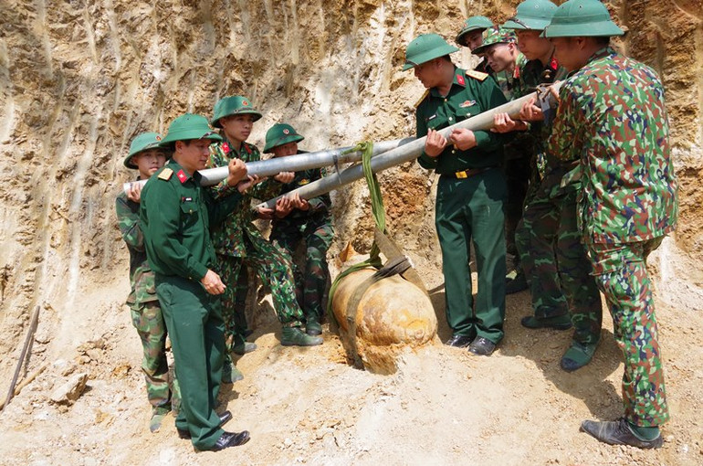 Di dời quả bom lên khỏi mặt đất. (Ảnh: HỒ TRÚC)