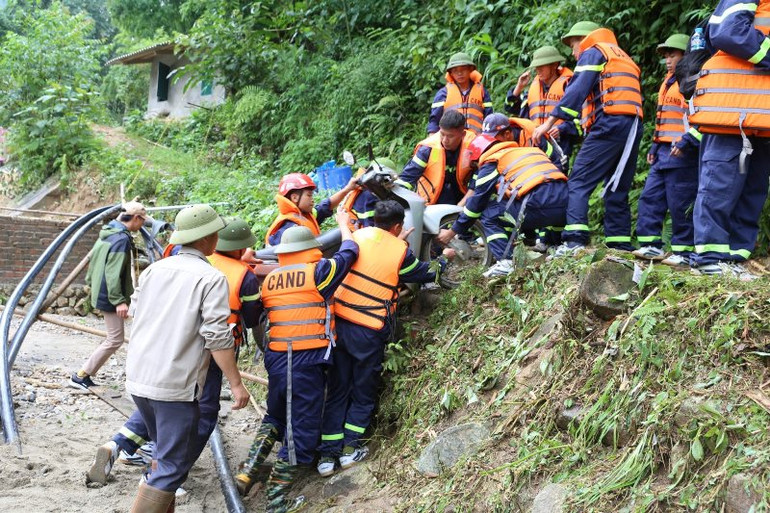 Giúp dân tìm kiếm tài sản bị vùi lấp sau cơn lũ ống tàn khốc. (Ảnh: QUỐC HỒNG)