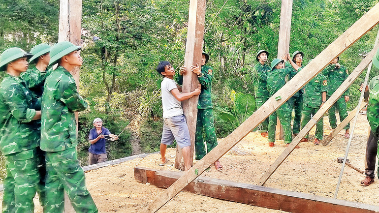 Cán bộ, chiến sĩ Ðồn Biên phòng Cà Xèng hỗ trợ dựng nhà mới cho hai em người Rục mồ côi cha mẹ.