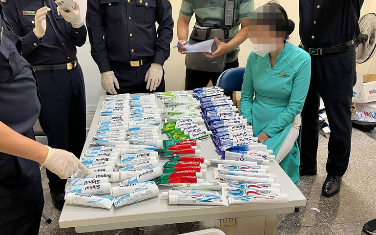 Một trong 4 tiếp viên hàng không bị bắt giữ (áo xanh, ngồi) cùng số tang vật vụ án.