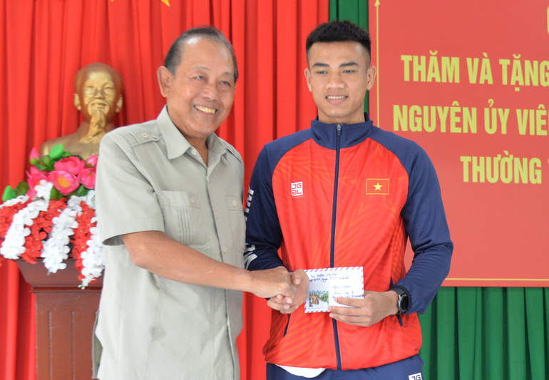 Đồng chí Trương Hòa Bình, nguyên Phó Thủ tướng Thường trực Chính phủ tặng quà chúc mừng vận động viên Đinh Văn Bí đã xuất sắc đoạt Huy chương vàng môn Wushu, hạng cân 70kg tại SEA Games 32.