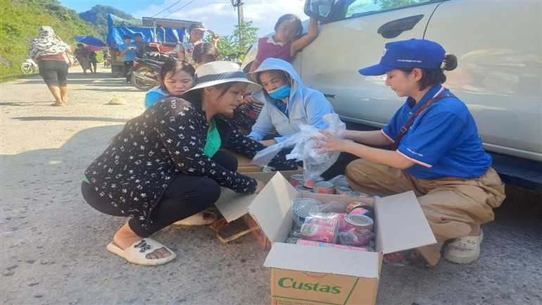 Đoàn từ thiện chia thịt hộp, cá hộp hỗ trợ người dân vùng lũ.