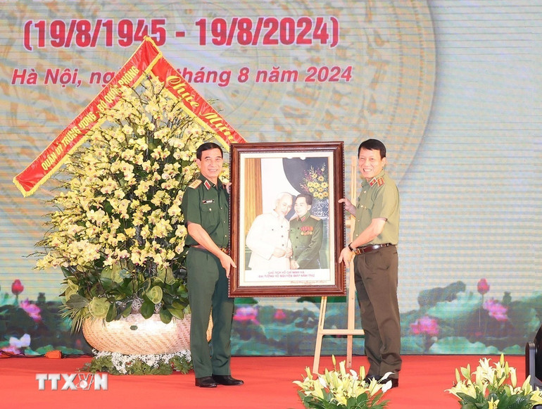 Đại tướng, Bộ trưởng Quốc phòng Phan Văn Giang, thay mặt Quân ủy Trung ương, Bộ Quốc phòng trao tặng bức ảnh Bác Hồ cho Thượng tướng, Bộ trưởng Công an Lương Tam Quang, thay mặt Đảng ủy Công an Trung ương, Bộ Công an. (Ảnh: Trí Dũng/TTXVN)