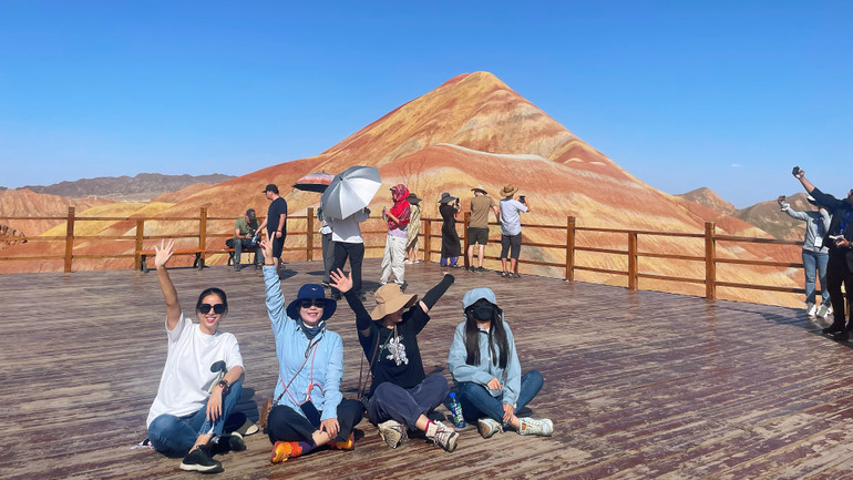 Du khách check-in bên khung cảnh núi đồi rực rỡ sắc màu. (Ảnh: HỮU HƯNG)