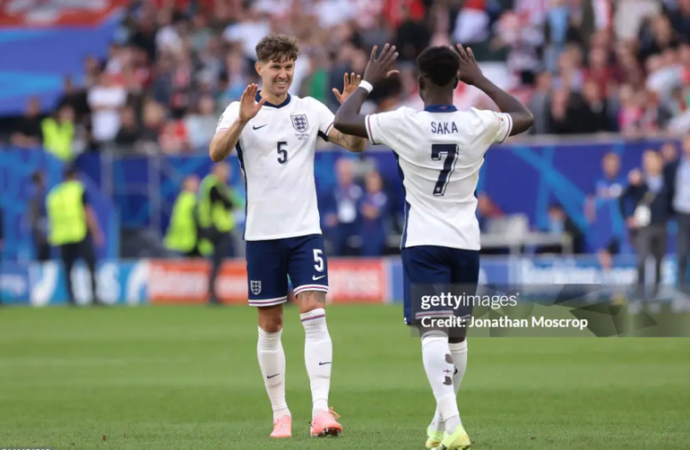 John Stones chúc mừng Saka sau lượt sút thành công. (Ảnh: Getty)