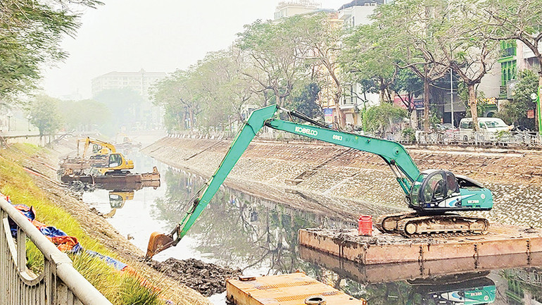 Tại phía thượng lưu sông Tô Lịch, hàng chục công nhân điều khiển hai dây chuyền thi công nạo vét bằng xe cơ giới kết hợp máy xúc trên sà-lan.