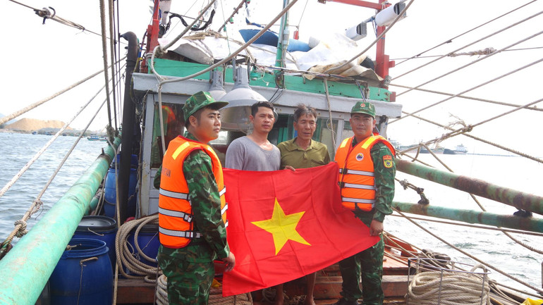 Cán bộ, chiến sĩ Đồn Biên phòng Cam Ranh tặng cờ cho ngư dân bám biển. (Ảnh: Bộ đội biên phòng tỉnh Khánh Hòa)