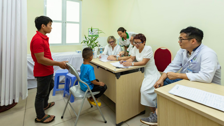 Các chuyên gia quốc tế và trong nước khám, đánh giá cho một bệnh nhi bị dị tật.