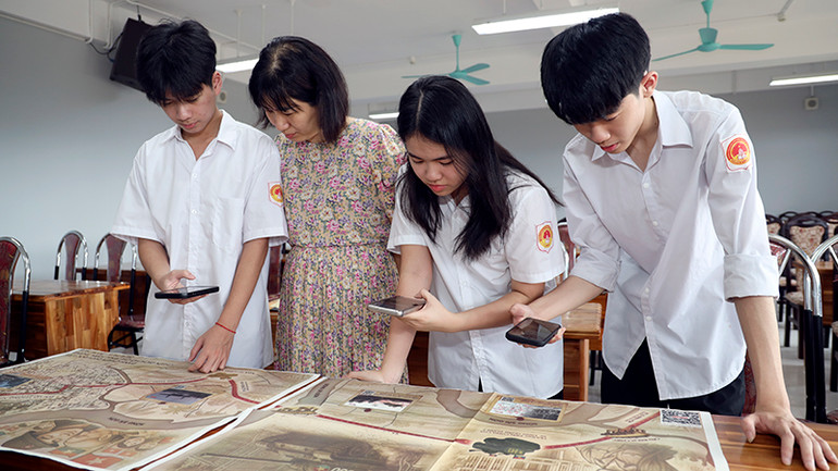 Cô giáo và học sinh Trường THPT Chuyên Tuyên Quang trải nghiệm công nghệ thực tế ảo trên phụ san đặc biệt do Báo Nhân Dân phát hành.