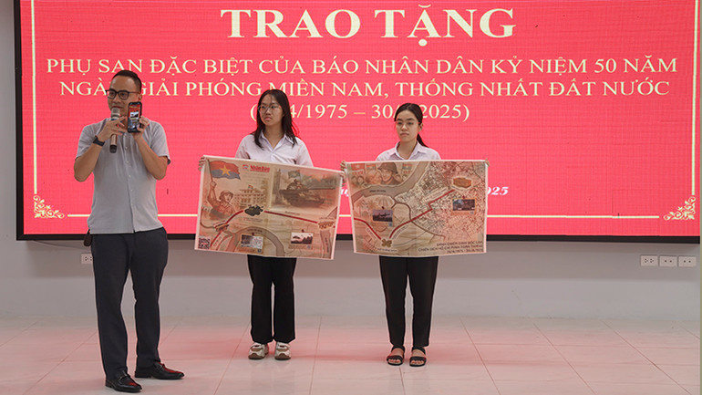 Phóng viên Văn phòng đại diện Báo Nhân Dân tại Tuyên Quang hướng dẫn các em học sinh quy trình quét mã QR để trải nghiệm phụ san.