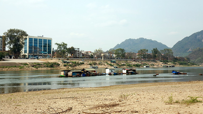 Người nuôi cá lồng trên sông Lô lựa dòng nước để di chuyển lồng nuôi cá đến nơi nước sâu hơn.