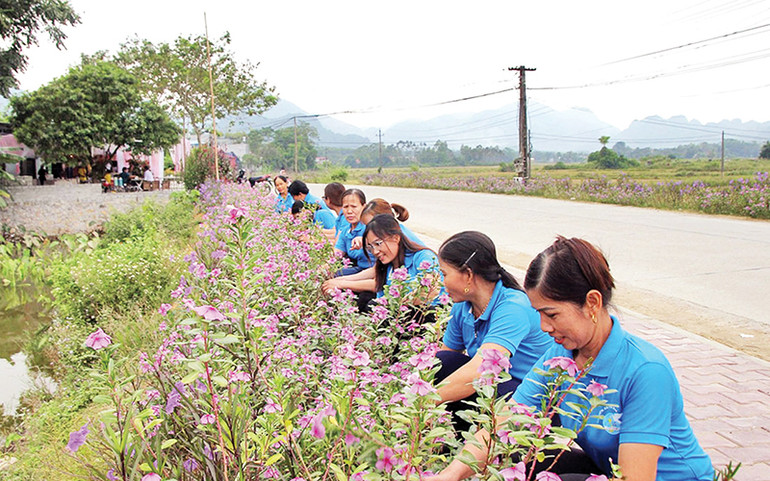 Phụ nữ xã Phúc Ứng, huyện Sơn Dương chăm sóc tuyến đường hoa. (Ảnh LÝ THU)