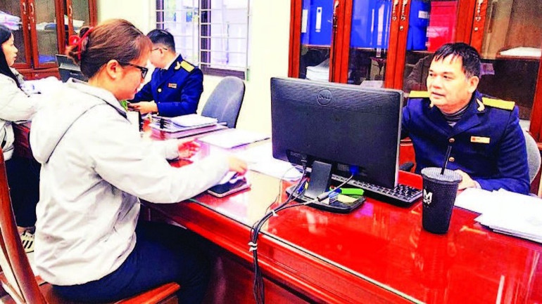 Công chức ngành thuế hướng dẫn người dân kê khai nộp thuế vào ngân sách nhà nước. (Ảnh HOÀI AN)