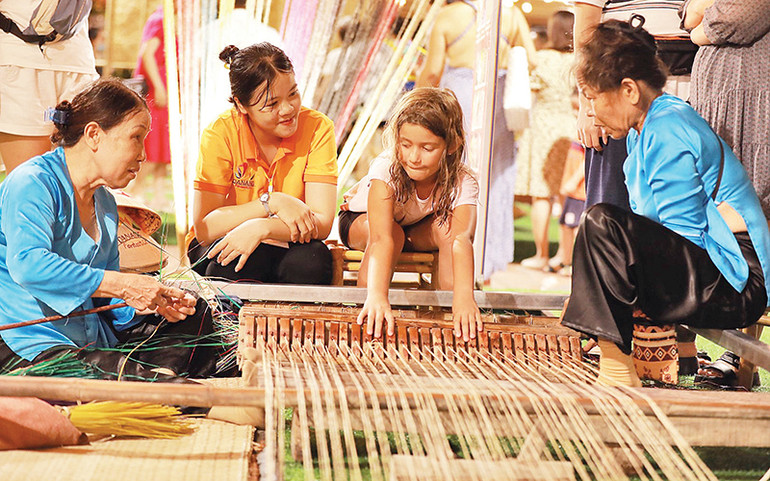 Du khách tham gia dệt thổ cẩm tại lễ hội.
