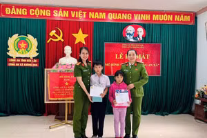 Đại diện Công an xã Krông Ana tặng quà cho con nuôi Đặng Hải Đăng và Hoàng Bảo Ngọc.