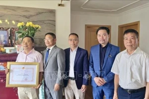 Tham tán Công sứ Chu Tuấn Đức (đứng giữa), Chủ tịch Hội Cựu chiến binh Việt Nam tại Cộng hòa liên bang Đức trao giấy khen, tri ân công lao của gia đình ông Lê Đình Bính có người thân là liệt sĩ. (Ảnh: PHƯƠNG HOA/PV TTXVN TẠI ĐỨC)