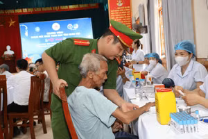 Cán bộ công an xã và nhân viên y tế hướng dẫn, hỗ trợ người dân đến khám sức khỏe.