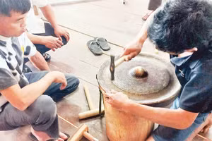 Các học viên thực hành chỉnh âm cồng chiêng tại lớp tập huấn do nhà nghiên cứu Bùi Trọng Hiền hướng dẫn. 