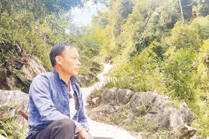 Bí thư Chi bộ Thào A Quả bên một đoạn đường anh đã vận động bà con chung sức hoàn thành. Ảnh: Doãn Hoàng 