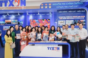 Cán bộ, phóng viên giới thiệu các sản phẩm thông tin chủ lực của TTXVN trưng bày tại Hội báo toàn quốc.