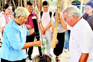 Vợ chồng ông Thạch Sang giã cốm dẹp cho khách du lịch xem.