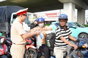 Cảnh sát giao thông Công an tỉnh Đồng Nai phát nước suối, khăn lạnh cho người dân trên Quốc lộ 1A.