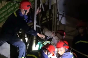 Lực lượng cứu hộ dùng dây, đai đưa ông T từ trên bảng quảng cáo xuống đất.