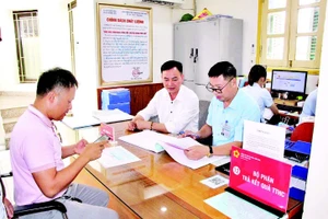 Cán bộ Trung tâm Phục vụ hành chính công phường Quảng Yên (tỉnh Quảng Ninh) hỗ trợ người dân làm thủ tục hành chính. (Ảnh QUANG THỌ)